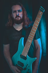 Atmospheric portrait of guitarist Patrick Taylor holding an electric guitar