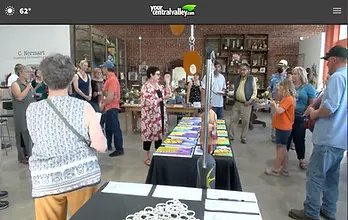 People crowd around tables with art on display and forms for their silent auction bids.