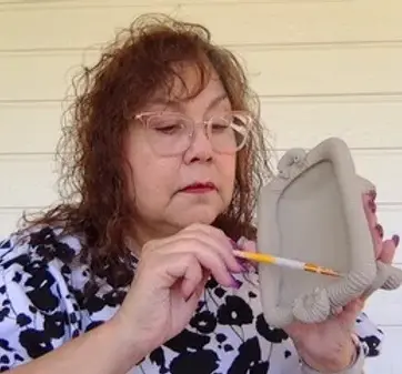 Dinorah is focused on adding details to a decorative hand built tray.