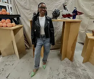 Tyler is pictured with ceramic works on tables behind her.
