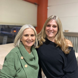 Good friends, Becky and Gale, are standing side by side posing for this picture in the arts studio.