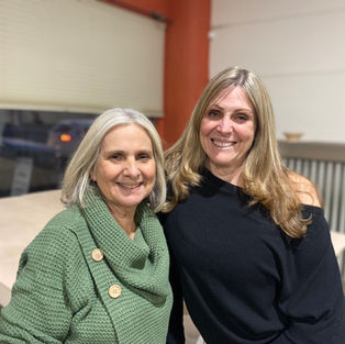 Good friends, Becky and Gale, are standing side by side posing for this picture in the arts studio.