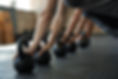Kettelbells on the floor in the gym and people in plank holding the kettelbell