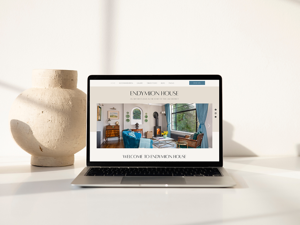 A laptop on a softly lit desk with a cream pot. The screen is showing the Endymion house website