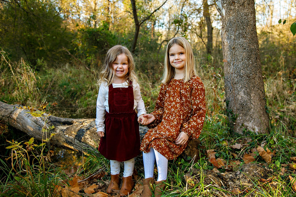 Two sisters holding hands in a fall outdoor wooded setting for a location photoshoot in Ka