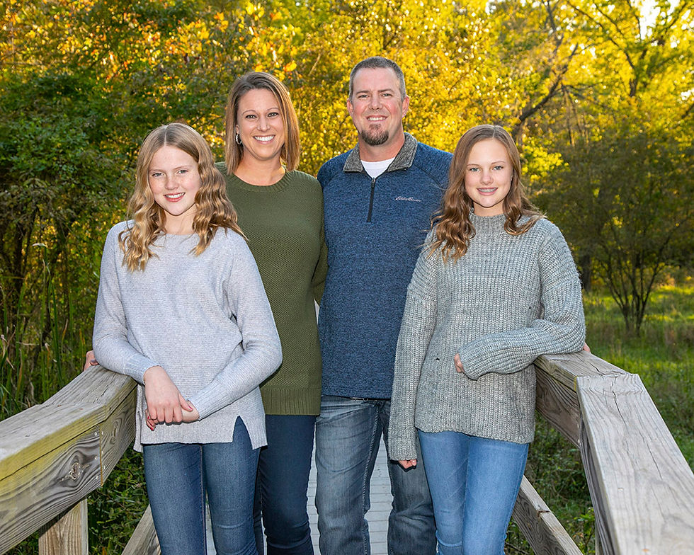 Family of four standing on a bridge in a fall outdoor setting in Kansas City