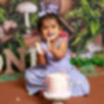 One year old girl lin
butterfly and mushroom fairyland background with cake covered hands and face.