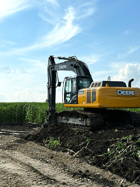 A Deere machine moving dirt in a field.