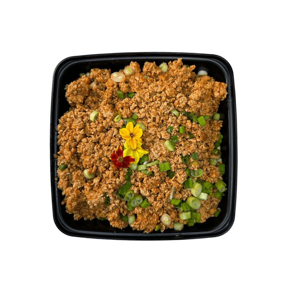 The LunaFit Fresh Taco Turkey 1lb Bulk sits in a square black container holding one pound of taco-seasoned ground turkey, garnished with diced green onions and a bright yellow edible flower.