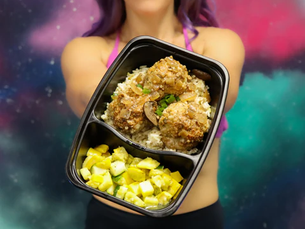 Woman in a colorful space-themed background holds a meal tray with prepped food.  Purple top, smiling expression.