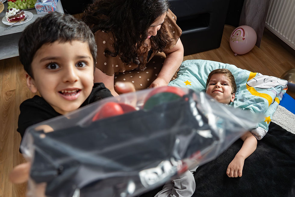 Junge mit behindertem Bruder zeigt Geschenk in Kamera von Familienfotografin Solingen