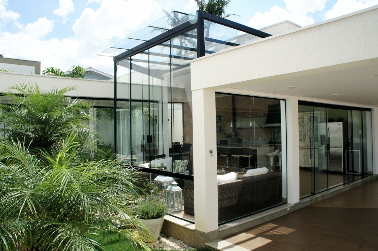 Estrutura moderna de pérgola fechada em vidro com perfis em alumínio preto, integrada à varanda gourmet e à fachada contemporânea, permitindo abundante entrada de iluminação natural e proteção contra intempéries feito pela RM Arquitetura em Atibaia