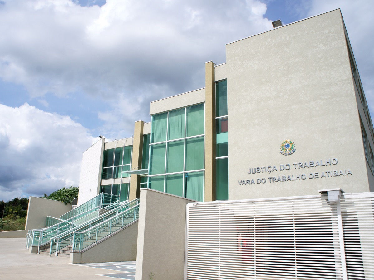 Fachada institucional imponente e moderna do prédio da Justiça do Trabalho - Vara do Trabalho de Atibaia, destacando a arquitetura corporativa com grandes panos de vidro verde refletivo, projeto feito pela RM Arquitetura em Atibaia