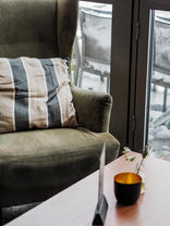 Gemütliche Lounge-Ecke bei fritzis Cafe & Bar mit einem bequemen Polstersessel, Dekokissen und minimalistischer Tischdeko für eine entspannte Kaffeepause.