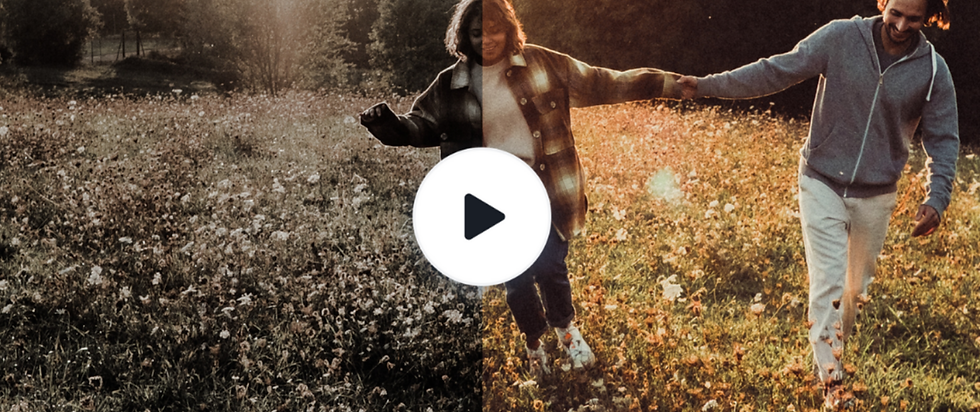 A couple holds hands, walking joyfully through a sunlit field of flowers. A large play button overlays the center, suggesting a video.