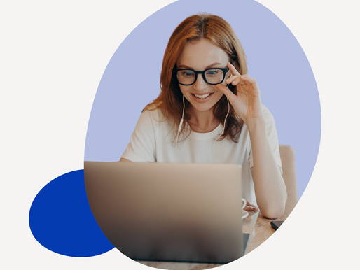 Woman in glasses smiling at a laptop.