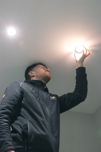 A commercial electrician working on a light at a business.