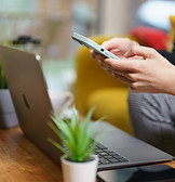 Man on phone in front of laptop, symbolizing easy, virtual access to mental health support and contact options.