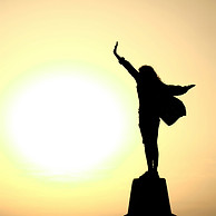 Person in an empowerment pose with the sun in the background, symbolizing strength, hope, and personal growth.
