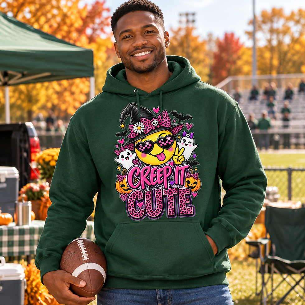Man wearing a Forest Green Creep It Cute Halloween hoodie while holding a football at a fall tailgate.