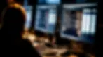Cybersecurity professional working in a dark room, analyzing code and threat data on multiple monitors during a red team penetration testing operation.