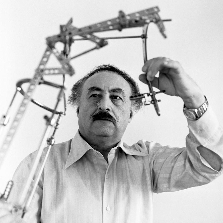 **Alt Text**: "Imagem em preto e branco de uma técnica médica desenvolvida na década de 1950 pelo Dr. Gavriil Abramovich Ilizarov. A técnica é usada para tratar fraturas complexas, deformidades e para alongamento ósseo. O método envolve um fixador externo circular modular, composto por anéis de aço inoxidável ou titânio, conectados por hastes roscadas. Esses anéis são fixados ao osso com pinos ou fios de Kirschner tensionados, proporcionando grande estabilidade estrutural."