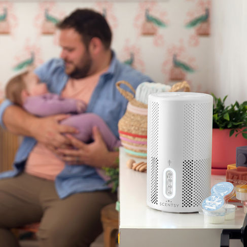 Father rocking a child & a Scentsy Air Purifier