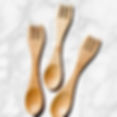 Three large bamboo sporks spread out on a kitchen counter