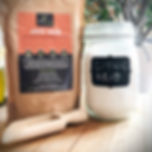 Large pack of citric acid crystals next to a storage jar and wooden scoop on a kitchen counter