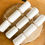 Thumbnail: Three homemade crackers made of white card resting on a wooden table