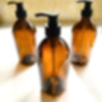 Three 500ml amber glass bottles with pump heads arranged on a white counter
