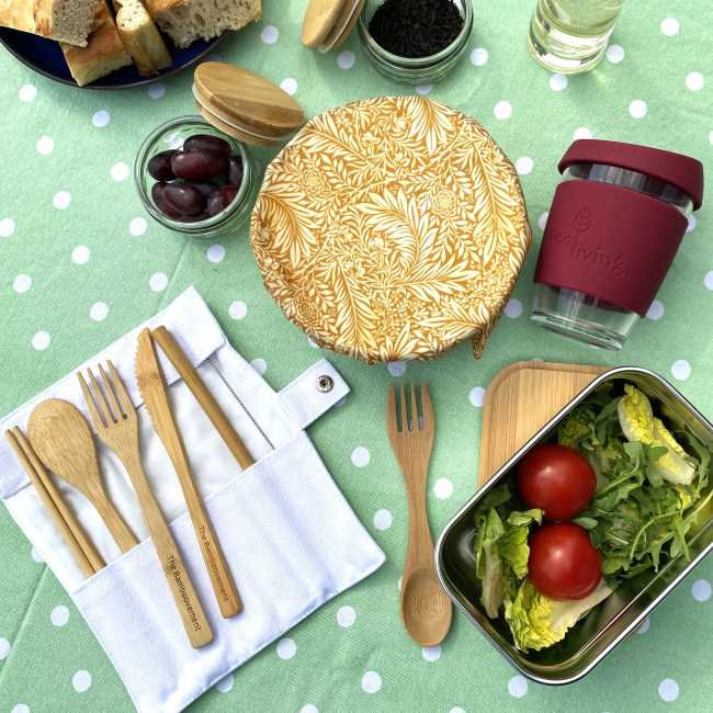 Thumbnail: Roll of reusable bamboo cutlery on a tablecloth with picnic food items