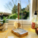 Wooden dish brush hanging on a plastic-free dish brush stand, on a kitchen windowsill