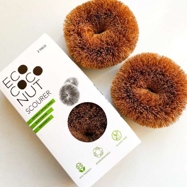Two plastic-free kitchen scourers made from coconut coir, next to their packaging