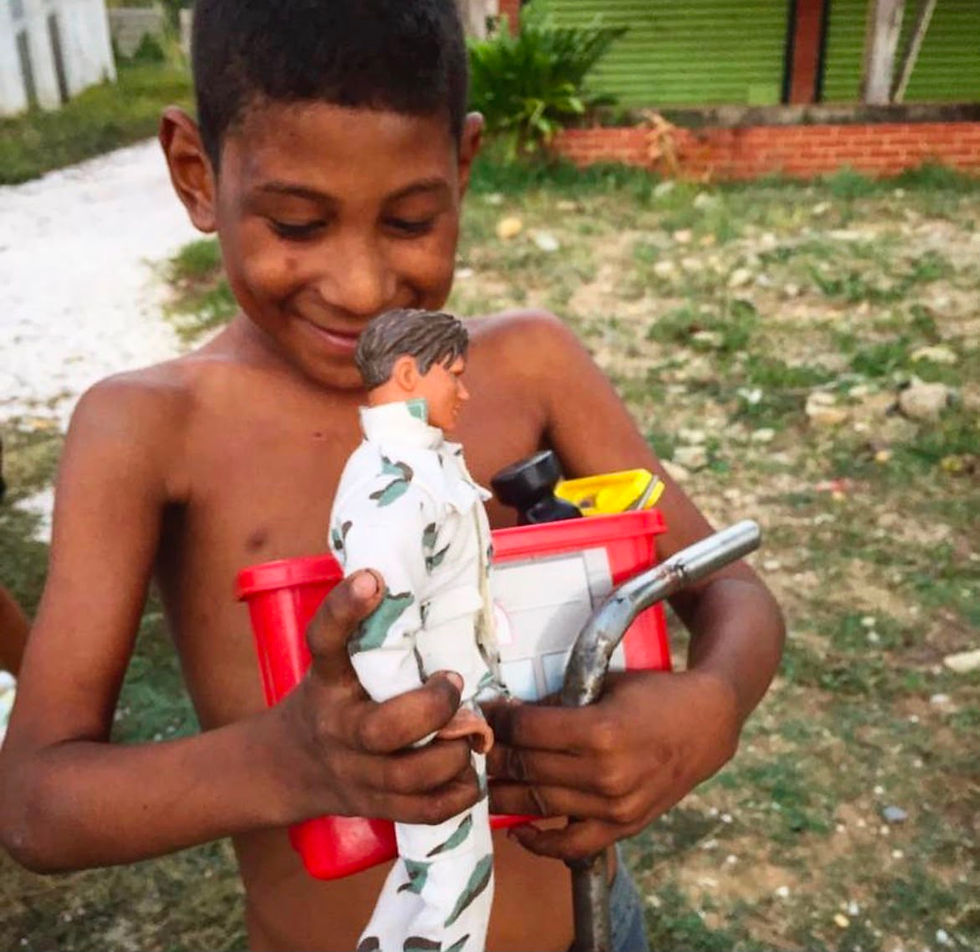 Boy smiling while holding toys, showing our impact.