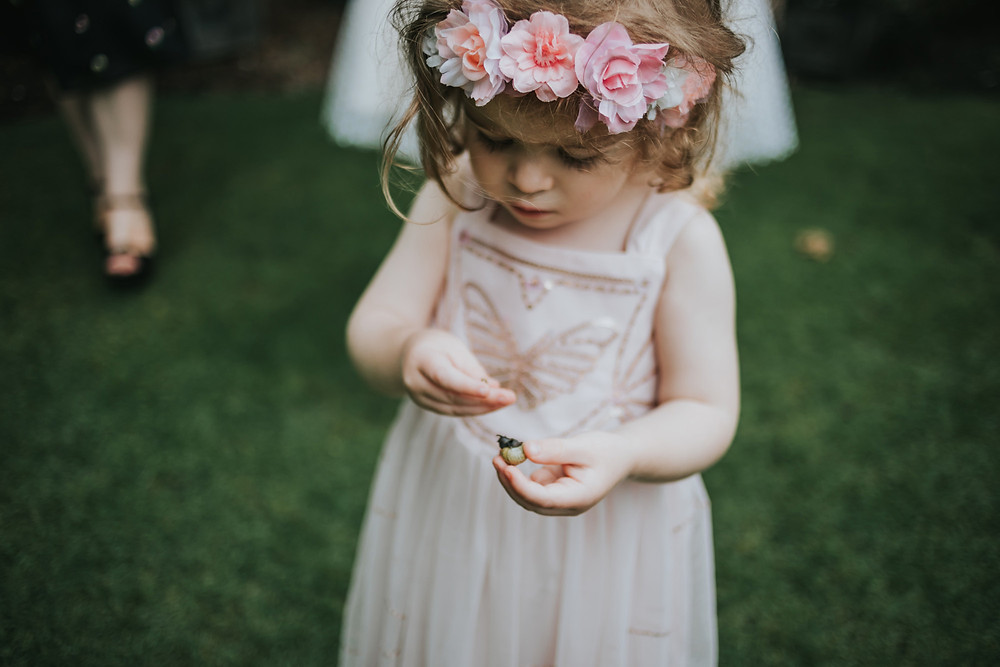 flower girl holding a snail in the gardens at holdsworth house
