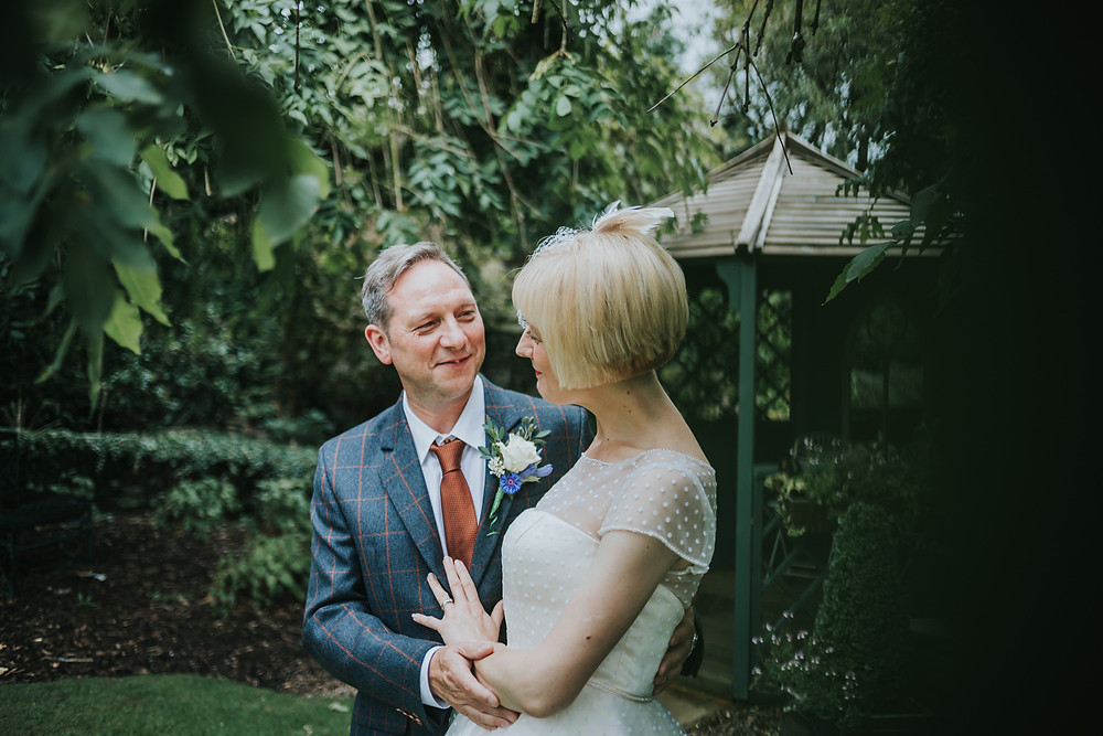 bride and groom smile at each other in the gardens at holdsworth house, halifax