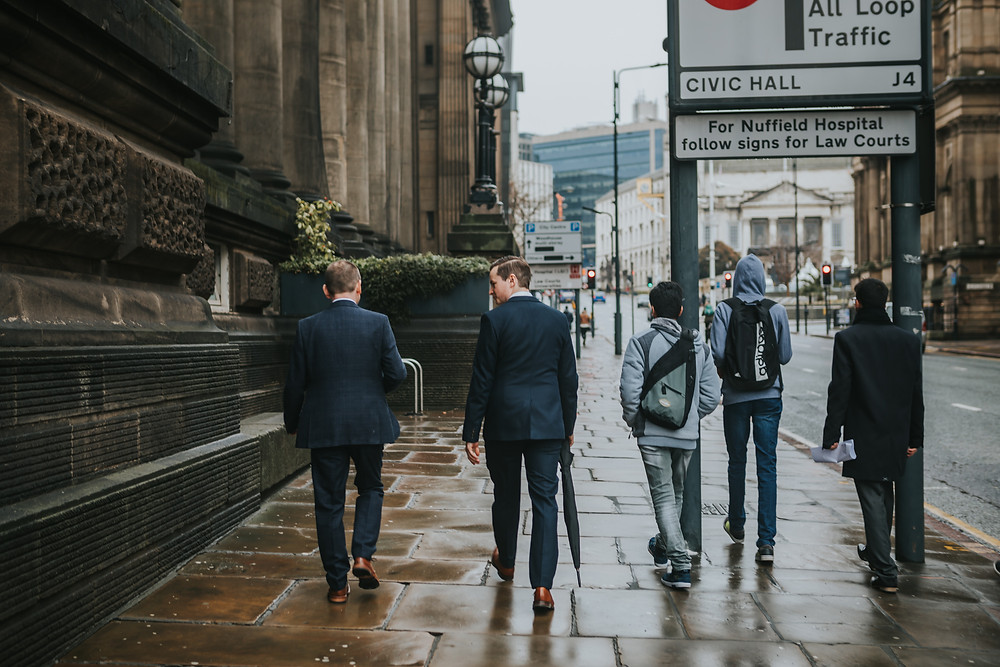 Groom and best man walking past Leeds Town Hall
