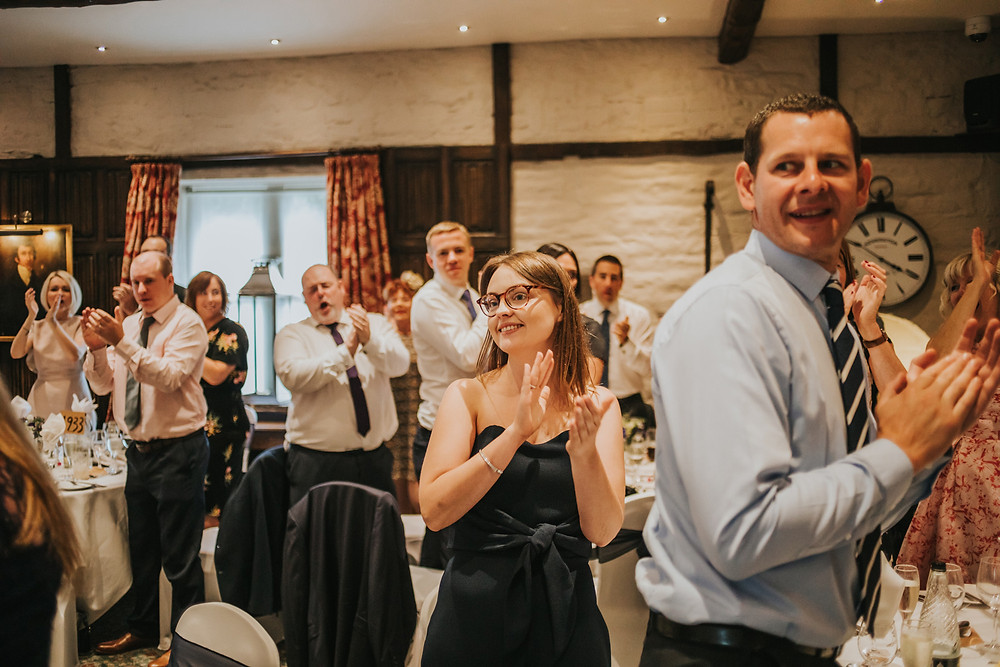 guests clapping as the couples enter the room for the wedding breakfast