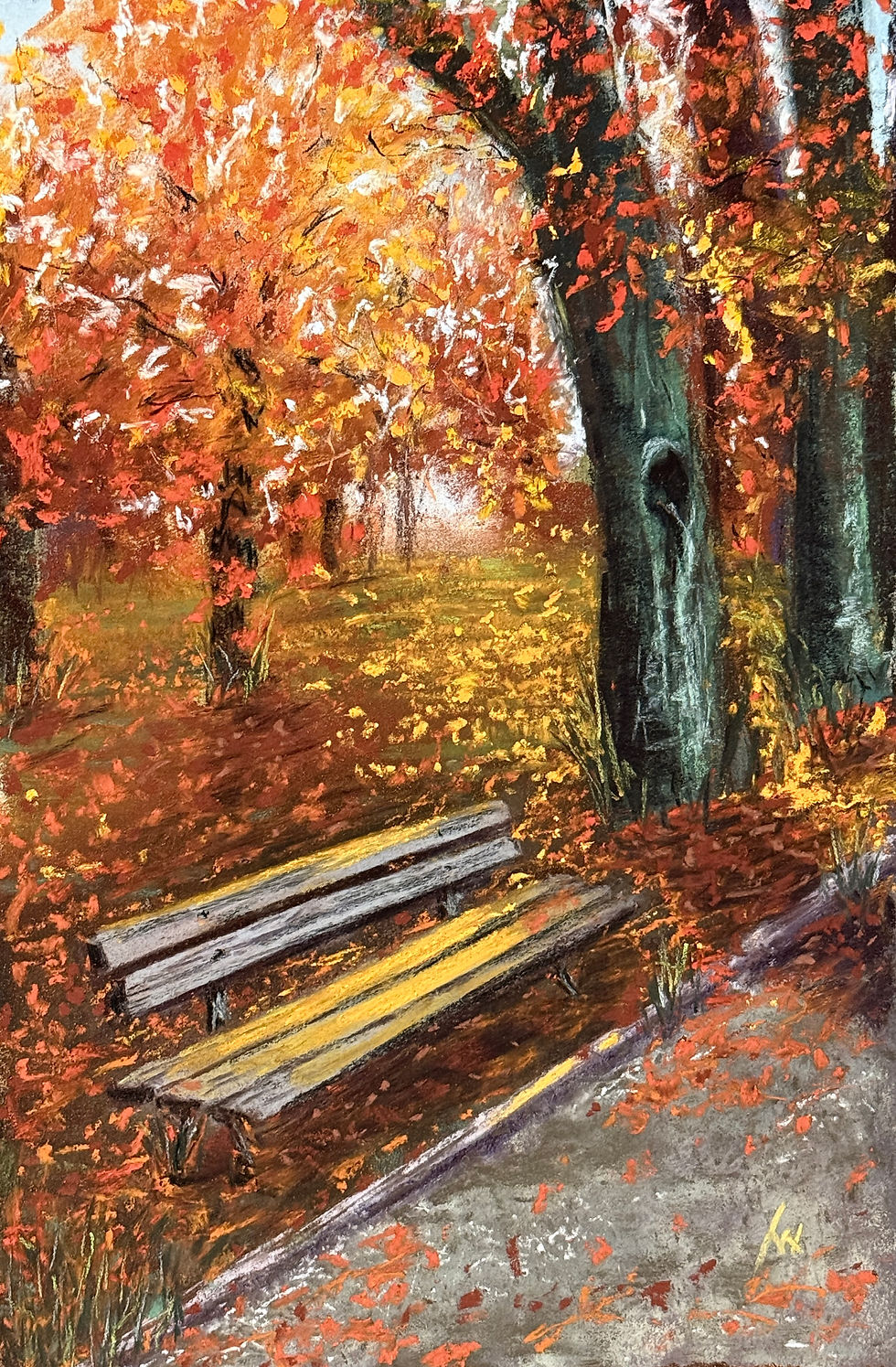 A wooden park bench reflects the orange sunset shining between fall trees, with lots of orange leaves scattered on the ground.