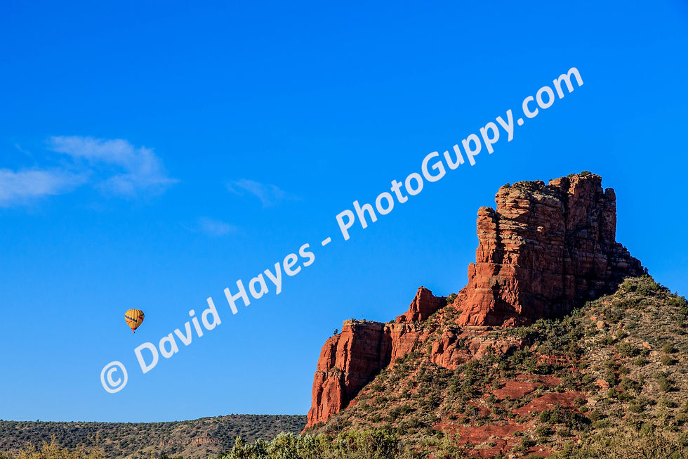 Hot air balloon sailing past giant red sandstone butte, Sedona, Arizona