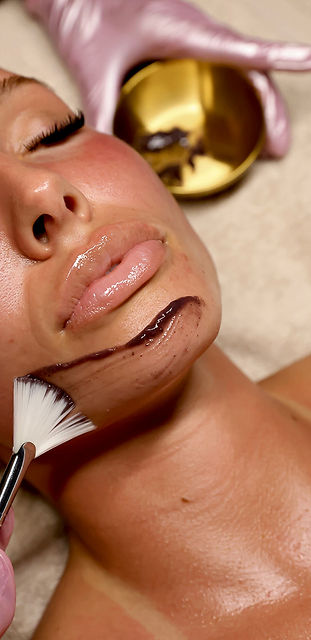 Axie, owner of Faced Esthetics in Wichita, KS, holding facial tools to promote the studio's facial services.