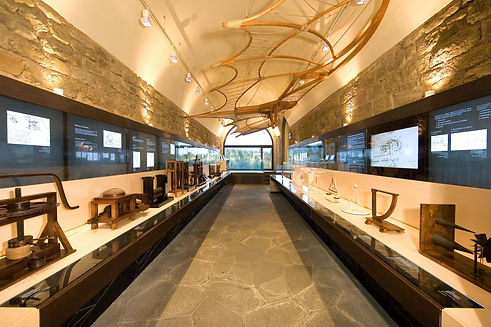 Interior view of the Leonardo da Vinci museum in Tuscany, showcasing various inventions and designs displayed along a well-lit corridor