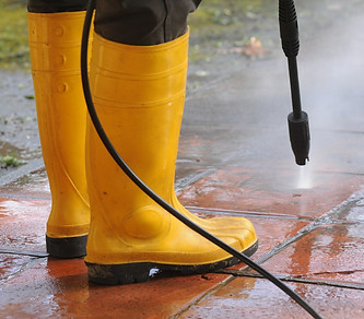 person-wearing-yellow-rubber-boots-with-high-pressure-water-nozzle-cleaning-dirt-tiles.jpg