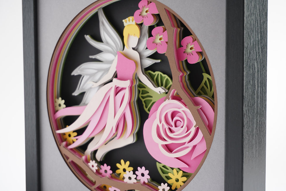 Thumbnail: Black framed 3D shadow box of a fairy princess wearing shades of pink with white wings surrounded by flowers