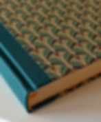 Nahaufnahme eines handgebundenen Tagebuchs mit Buchleinen und einem gold-grün gemusterten Papier.