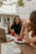 Women discussing online cleaning business summit ideas at a cafe.