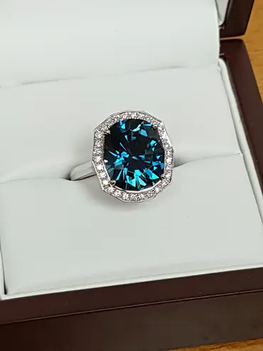 A platinum and diamond halo ring, with a large Deep London Blue Topaz in the centre.