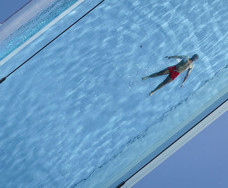 Urban photograph of man swimming in pool from below