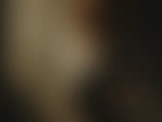 A powerful, painterly portrait of a young Jewish woman standing in soft golden light streaming through a tall window. She gazes upward with closed eyes and a serene, determined expression, her curly hair illuminated, wearing a simple white blouse and dark skirt. She holds a folded white paper (symbolizing her Get application) close to her chest, conveying quiet strength, hope, and emerging agency after hardship.